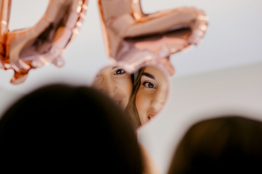 Marie and her friend smiling as they see themselves in a heart-shaped mirror | Esthesis Events