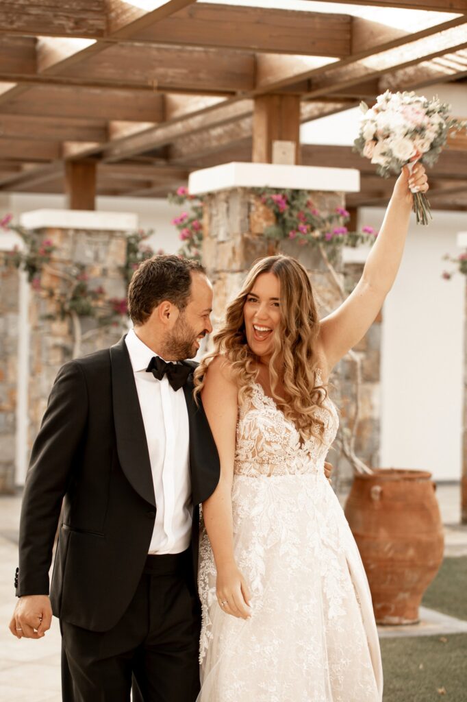 Marie holds the bridal bouquet high as Theodore smiles at her | Esthesis Events