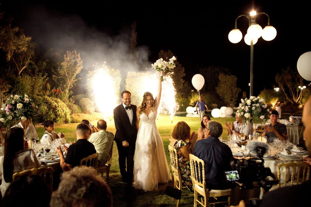 Marie and Theodore celebrating their wedding among friends and family, with sparklers going off in the backround | Esthesis Events