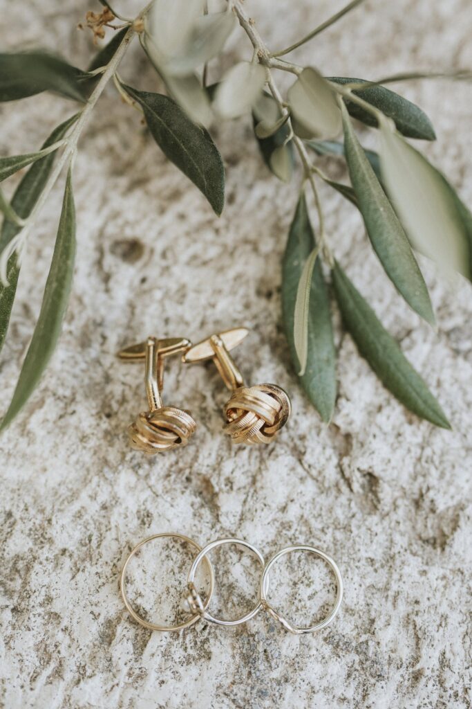 A detail shot of the wedding rings and Jodie's earrings arranged with fresh olive leaves. | Esthesis Events A detail shot of the wedding rings and Jodie's earrings arranged with fresh olive leaves. | Esthesis Events