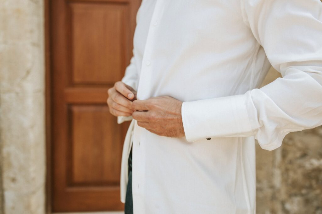 Michael buttoning his dress shirt while getting ready. | Esthesis Events Michael buttoning his dress shirt while getting ready. | Esthesis Events