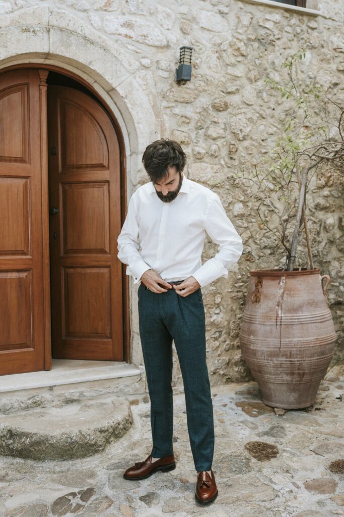 Michael fastening his belt while getting ready for the wedding. | Esthesis Events Michael fastening his belt while getting ready for the wedding. | Esthesis Events