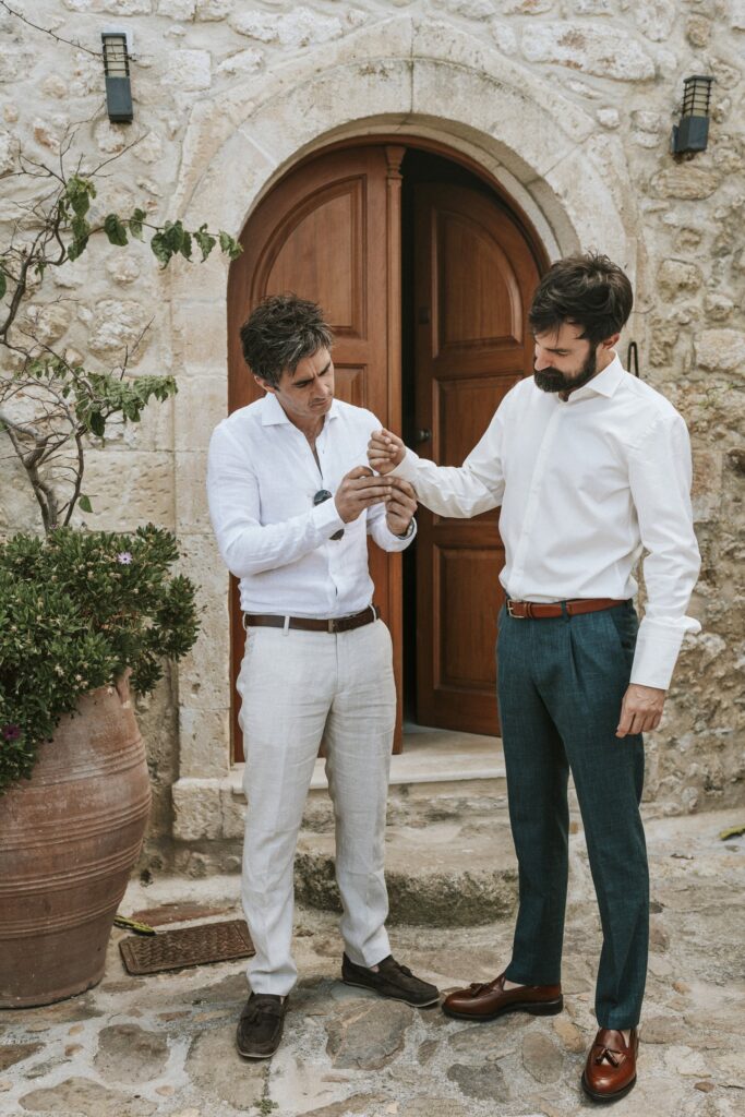 A groomsman helping Michael fasten his cufflinks before the wedding. | Esthesis Events A groomsman helping Michael fasten his cufflinks before the wedding. | Esthesis Events
