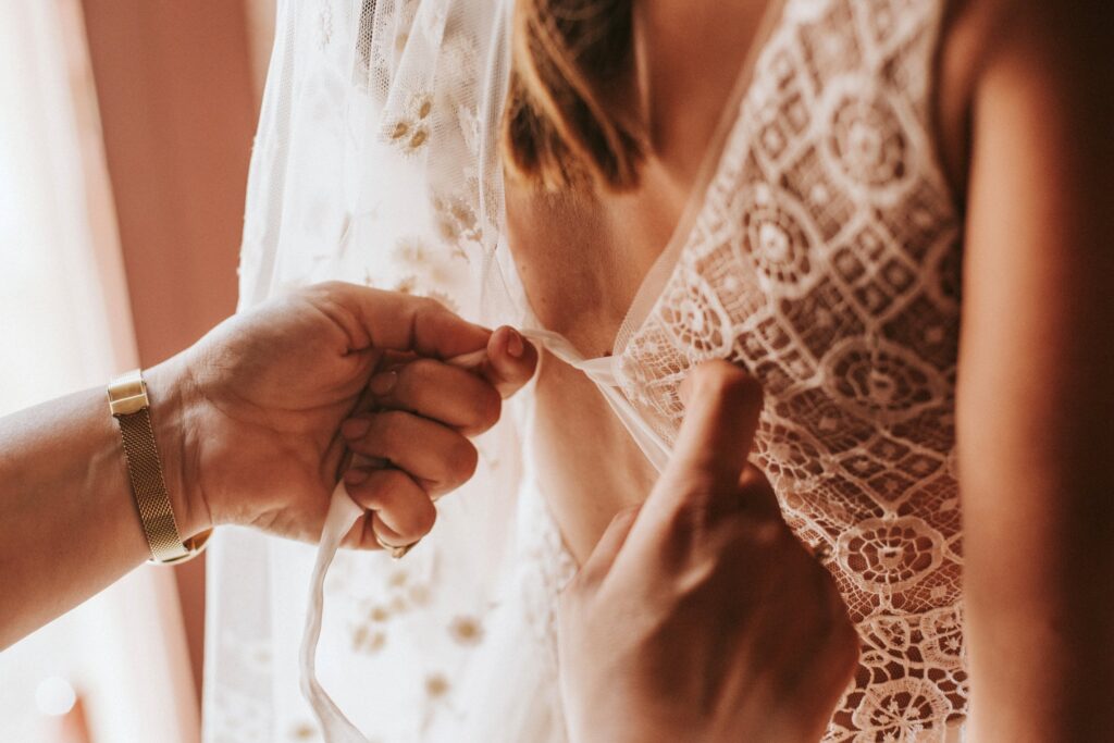 A loved one helping Jodie lace up the back of her wedding dress. | Esthesis Events A loved one helping Jodie lace up the back of her wedding dress. | Esthesis Events