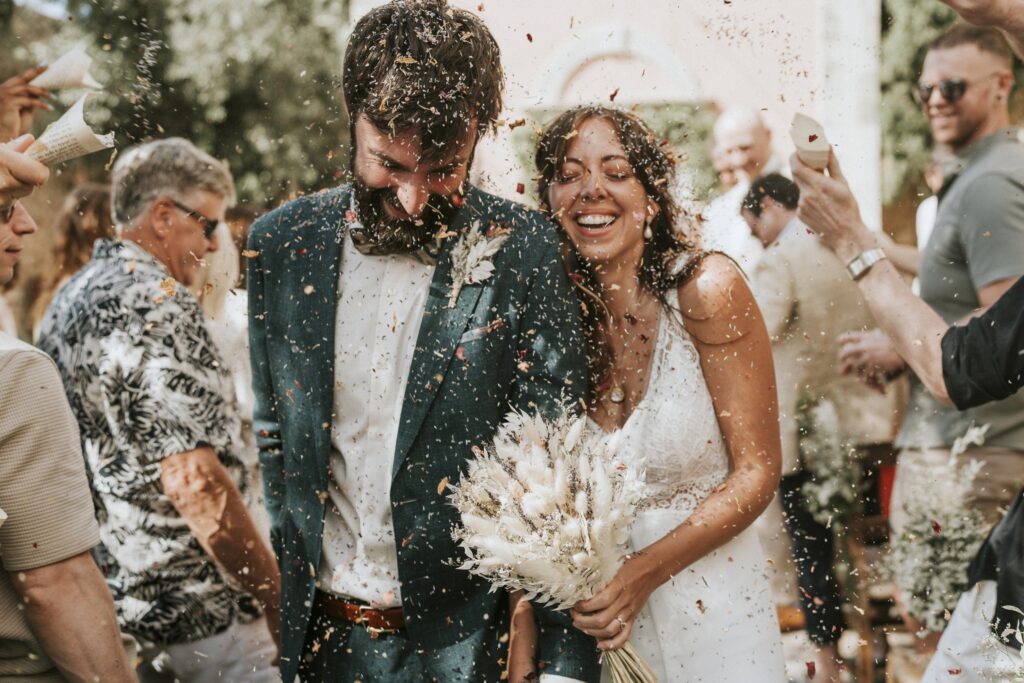 Michael and Jodie smiling as guests toss rice during their ceremony exit. | Esthesis Events Michael and Jodie smiling as guests toss rice during their ceremony exit. | Esthesis Events