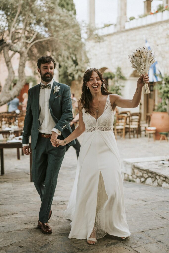 The newlyweds holding hands while the bride, Jodie, raises her bouquet in celebration. | Esthesis Events The newlyweds holding hands while the bride, Jodie, raises her bouquet in celebration. | Esthesis Events