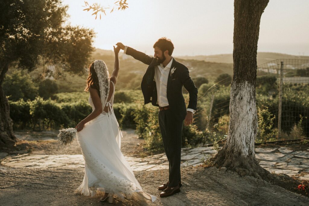 Michael holding Jodie's arm as she gracefully twirls in the olive garden at Agreco Farm. | Esthesis Events Michael holding Jodie's arm as she gracefully twirls in the olive garden at Agreco Farm. | Esthesis Events
