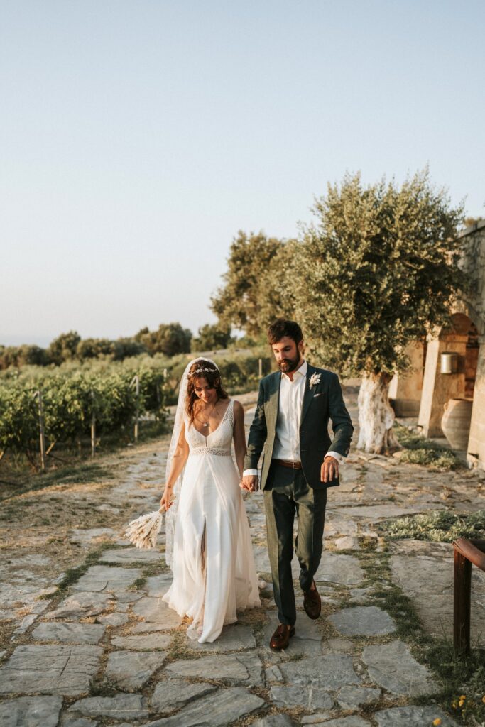 A romantic shot of the bride and groom walking hand-in-hand in the lush garden at Agreco Farm. | Esthesis Events A romantic shot of the bride and groom walking hand-in-hand in the lush garden at Agreco Farm. | Esthesis Events